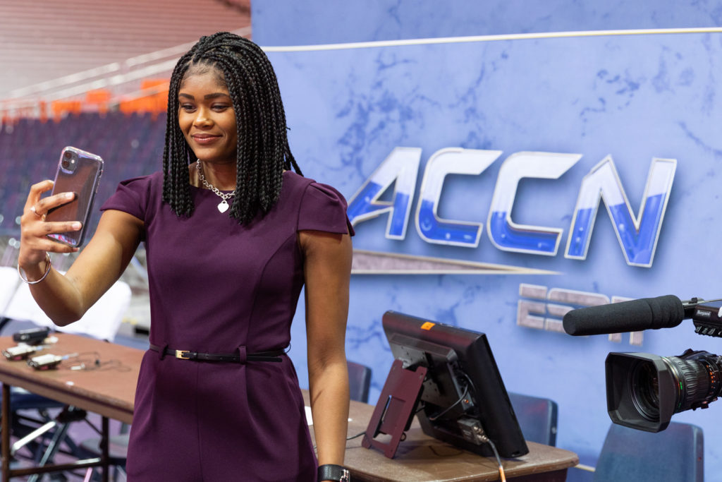 A student taking a selfie in front of the ACC Network logo