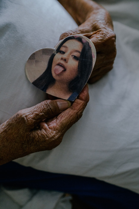 A senior woman's hands holding a heart-shaped cutout picture of a young girl with her tongue out.