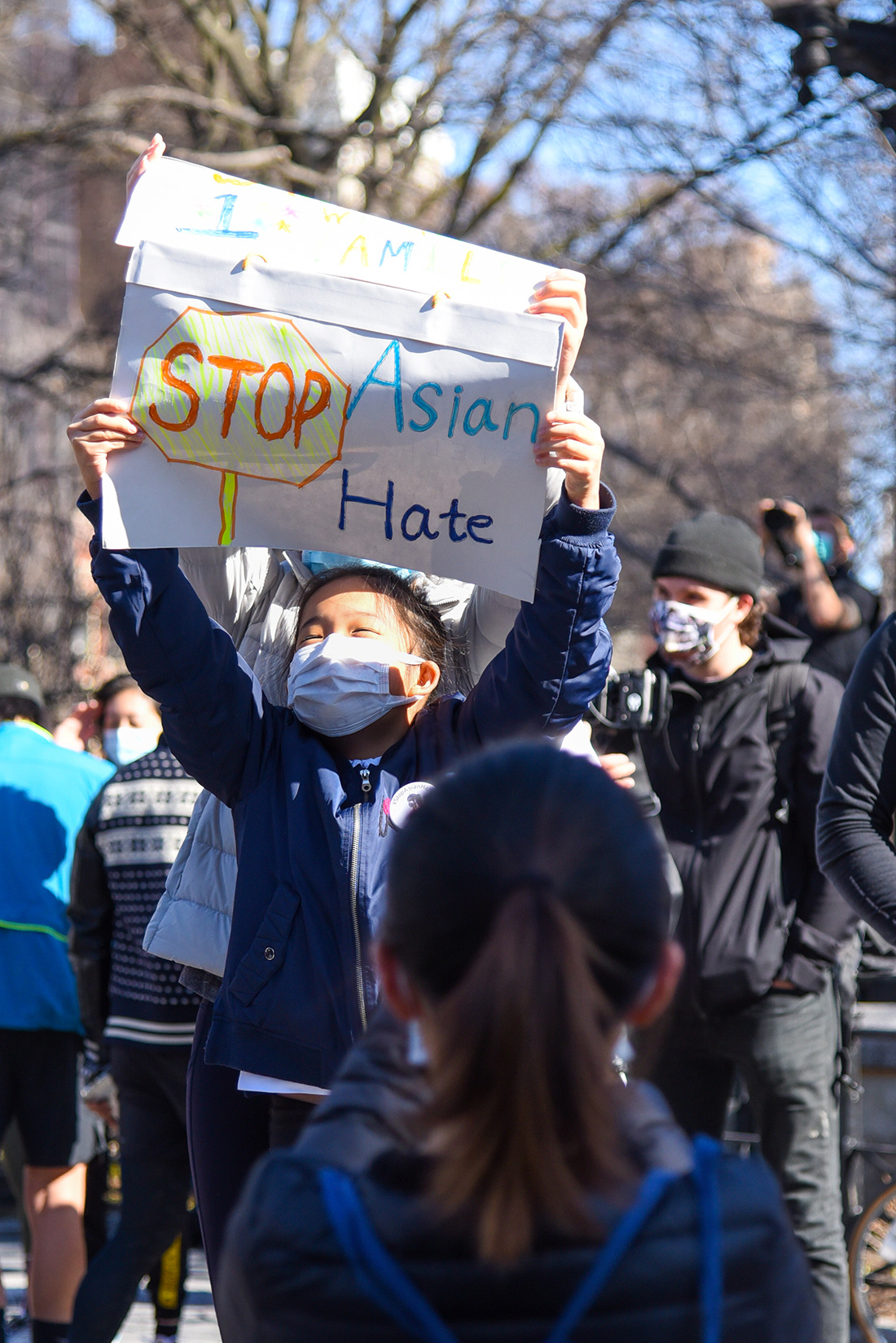 A young Asian girl wearing a mask holds a sign that reads "Stop Asian Hate" during the New York City protests.