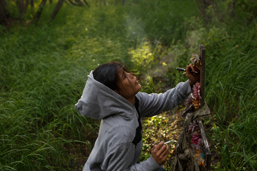 A young native woman signs a memorial in a field.