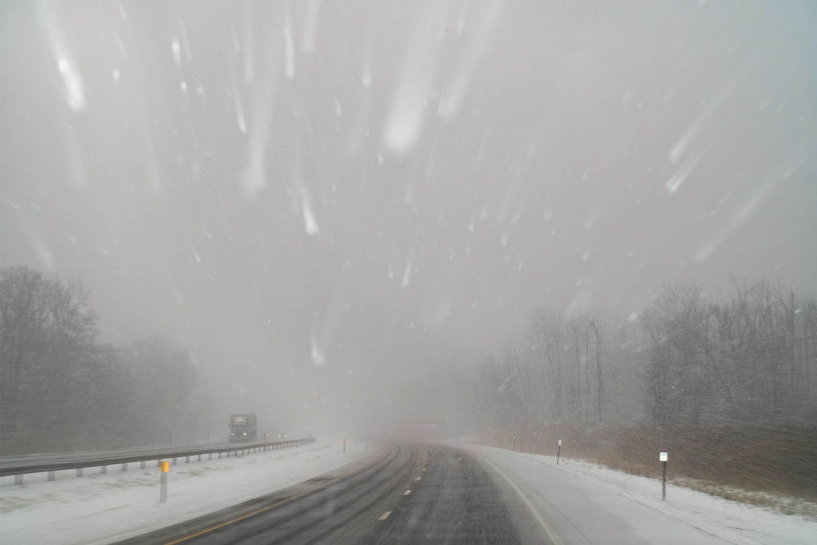 A snowy, gray day on the highway from the viewpoint of a driver.