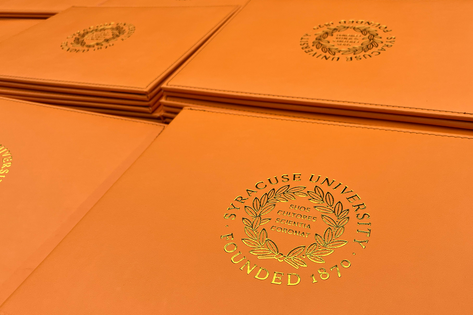 A stack of orange diploma covers