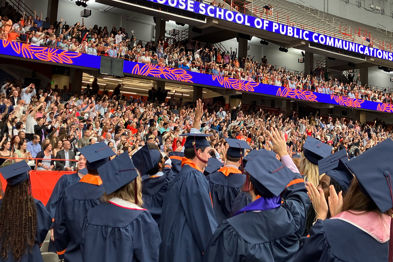 Graduates wave to family and friends in stands during the Newhouse Convocation Ceremony
